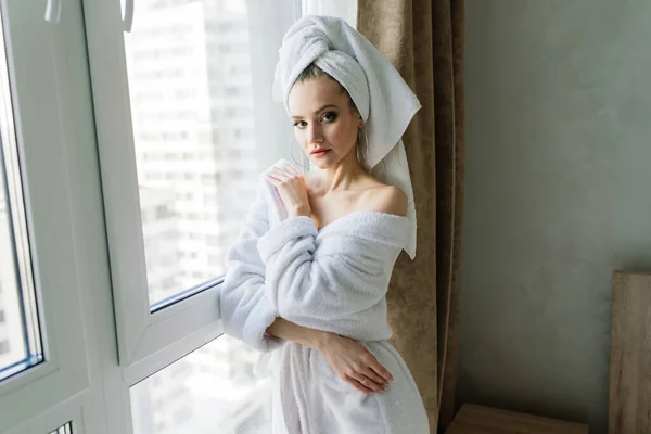 白いローブの女性は窓の近くとホテルの部屋のベッドの上に滞在 — ストック写真