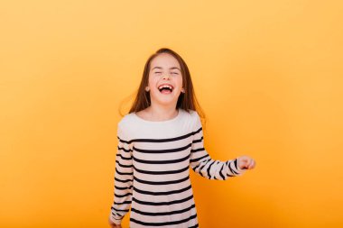 Güzel ve kendine güvenen bir kızın portresi sarı stüdyoda izole edilmiş duygularını gösteriyor.