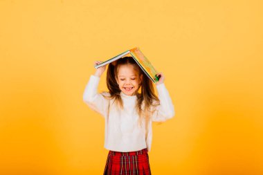 Mutlu, küçük, güzel bir kız çocuğu gri arka planda kameraya bakıyor..