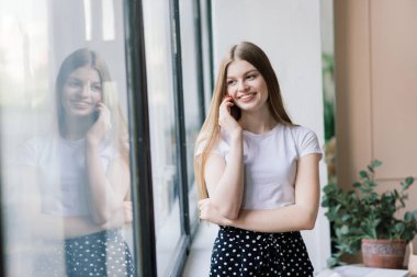 Genç ve çekici bir kadın evdeki beyaz kanepede dinleniyor.