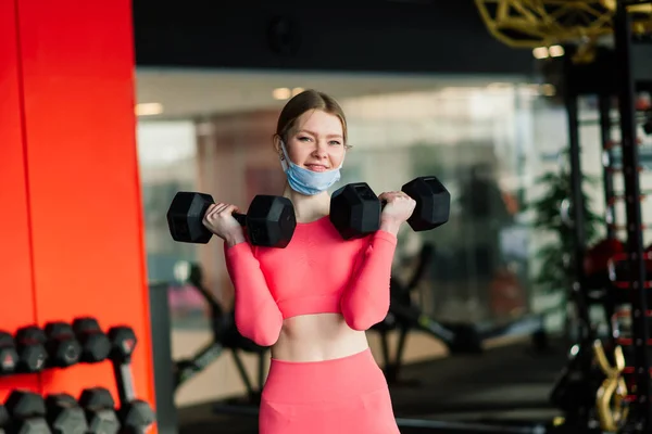 Woman wearing face mask exercise workout in gym during corona virus pandermic, covid