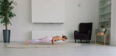 Genç bir kadın meditasyon yapıyor, yoga yapıyor evde, arkada, önde ve yanda.