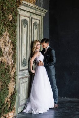 Klasik bir stüdyonun içinde şirin bir düğün çifti. Öpüşüyorlar ve sarılıyorlar..