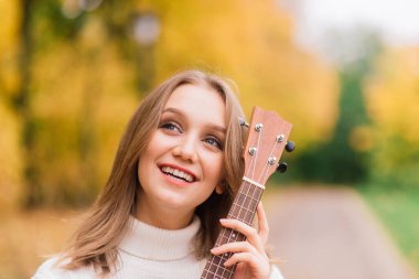 Güz ormanlarında gitar çalan güzel bir kadın.