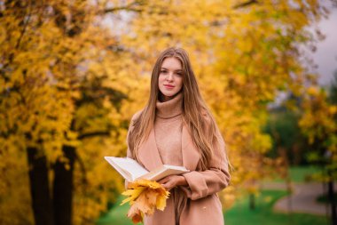 Güzel bir kadın sonbahar mevsiminde parkta vakit geçiriyor.