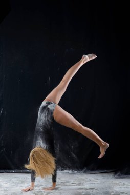 Uçan toz bulutlarıyla kaplı siyah jimnastik mayo giyen güzel sarışın kız.