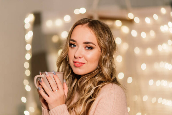 Happy young lady with long hair near fireplace and the Christmas tree, gifts. New year concept.