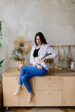 Genç ve çekici bir kadın evdeki beyaz kanepede dinleniyor.