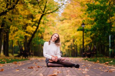 Güz ormanlarında gitar çalan güzel bir kadın.