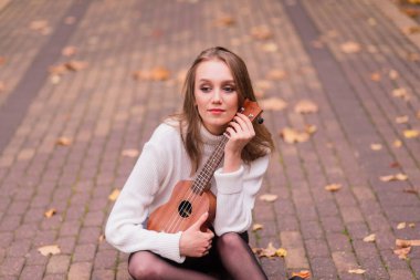 Güz ormanlarında gitar çalan güzel bir kadın.