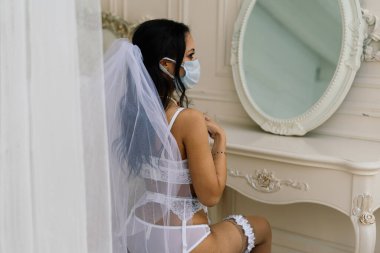 İç çamaşırlı, maskeli ve sabahleyin otel odasındaki düğüne hazırlanan Afrikalı Amerikalı gelin.