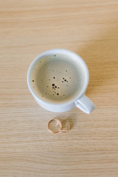 Coffee with wedding rings on table, morning of bride