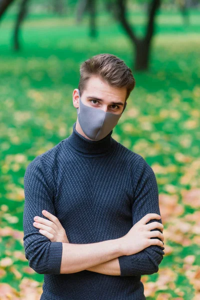 Young man in a flu mask in autumn park