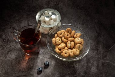 Bir cam kasede tarallini, bir bardak çay, ve cam şeker kasesi ile, gri benekli arka planda yabanmersini