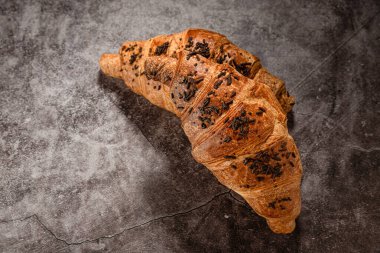 Gri benekli arka planda çikolata parçalı kruvasanlar.