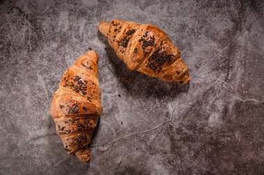 Gri benekli arka planda çikolata parçalı kruvasanlar.