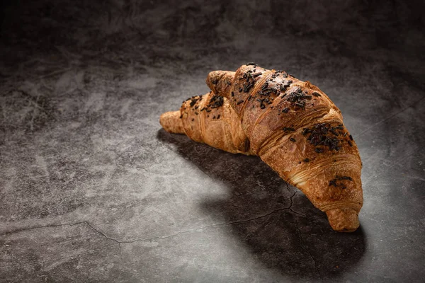 Croissants with chocolate chips on a gray mottled background