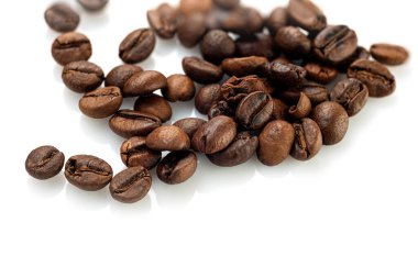 Kahve çekirdekleri beyaz arka planda rastgele dağılmış.