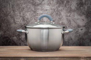 Food pan, stainless steel, on a wooden countertop, against a stuccoed wall