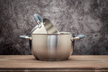 Food pan, stainless steel, on a wooden countertop, against a stuccoed wall