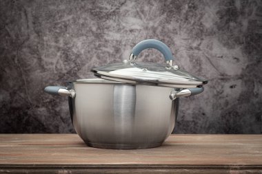 Food pan, stainless steel, on a wooden countertop, against a stuccoed wall