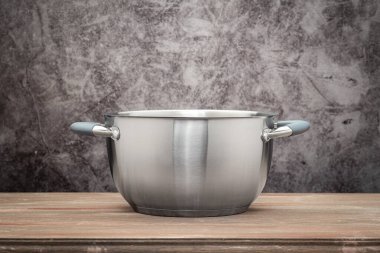 Food pan, stainless steel, on a wooden countertop, against a stuccoed wall