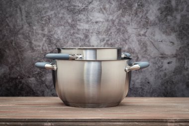 Food pan, stainless steel, on a wooden countertop, against a stuccoed wall