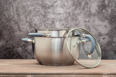 Food pan, stainless steel, on a wooden countertop, against a stuccoed wall