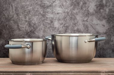 Food pan, stainless steel, on a wooden countertop, against a stuccoed wall