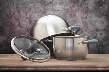Food pan, stainless steel, on a wooden countertop, against a stuccoed wall