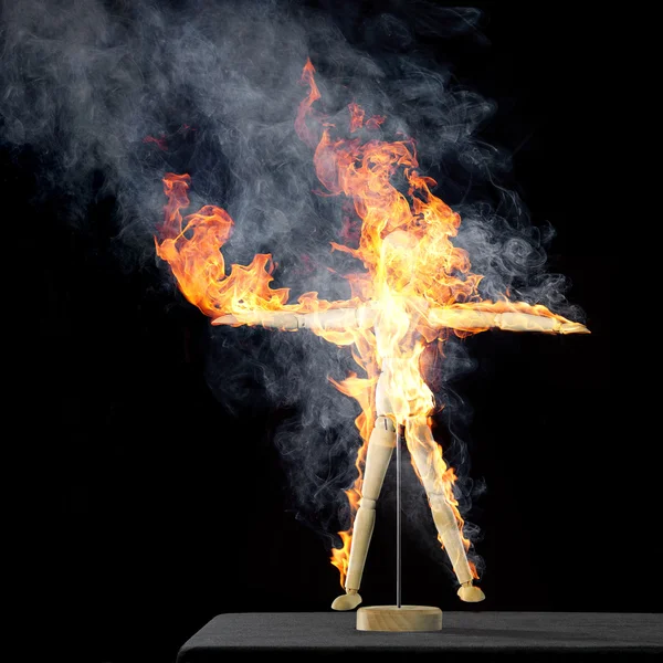 Burning wooden doll on desktop — Stock Photo, Image