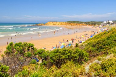 Tatilciler ve yerliler Point Danger, Torquay, Victoria, Avustralya 'daki kumlu sahilde harika vakit geçiriyorlar.