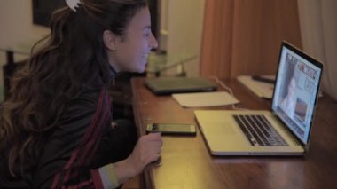 Mutlu kadın oturma odasında dijital bilgisayarla görüntülü konuşma yapıyor.