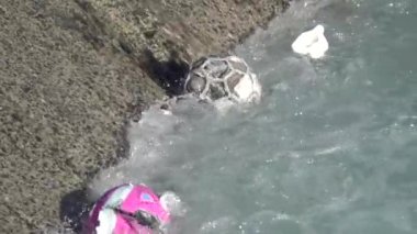 Kirlenmiş nehir çöpleri ve plastik toplar yavaş çekimde zıplıyor.