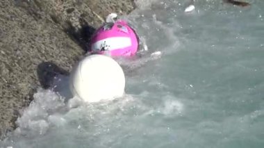 Kirlenmiş nehir çöpleri ve plastik toplar yavaş çekimde zıplıyor.