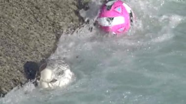 Kirlenmiş nehir çöpleri ve plastik toplar yavaş çekimde zıplıyor.