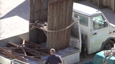 Veneto, İtalya - 9 Nisan 2021: İşçiler bir ev inşaatı için bir kamyona metal yapı yüklüyorlar