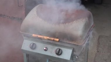 Yaşlı BBQ içicisinden duman yükseliyor. Kapat.