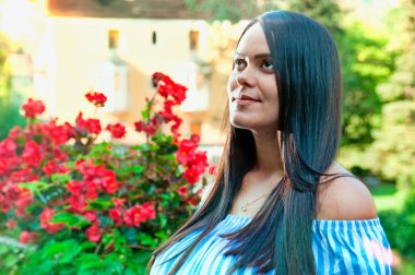 Gülümseyen mutlu Latin Amerikalı kadının portresi, ağaçların ve çiçeklerin izole edilmiş arka planı. Olumlu insani duygu