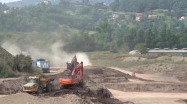 Çöp kamyonu ve kazıcı iş başında. Çıkarma. Kazıcı toprağı bir çöp kamyonunun içine dolduruyor.