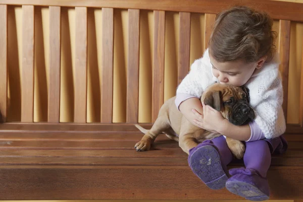 Kinderen meisje zoenen en knuffelen haar hond puppy — Stockfoto