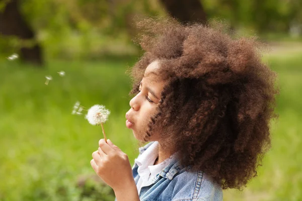 Mooi meisje blazen op een paardebloem — Stockfoto