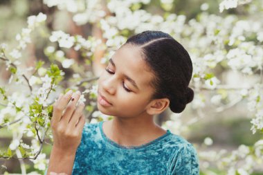 Etrafı çiçek açan ağaçlarla çevrili güzel bir kız. Baharda yanağında bir uğur böceğiyle.