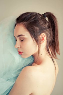 Portrait of serene beautiful woman holding light fabric