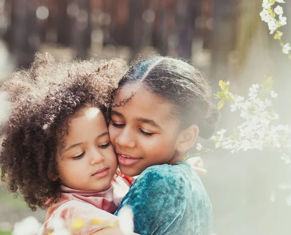 Sweet family portrait of two adorable sisters in springtime garden