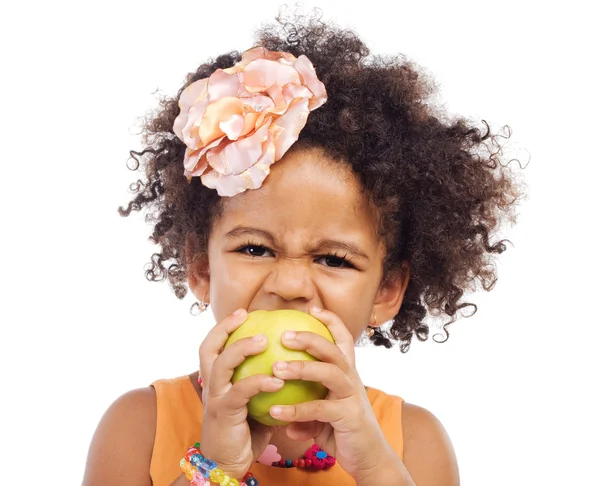 Angry little girl biting an apple — Stock Photo, Image