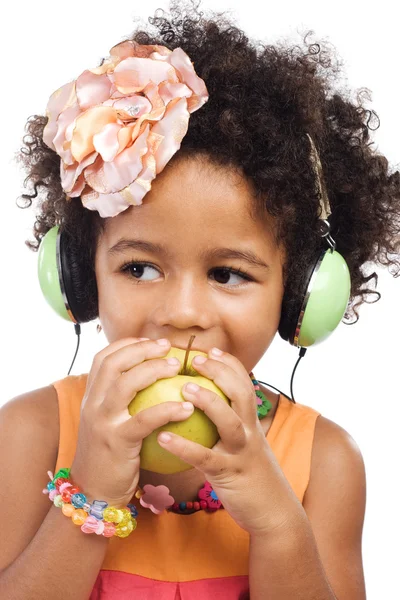 Cute girl in big headphones biting an apple — Stock Photo, Image