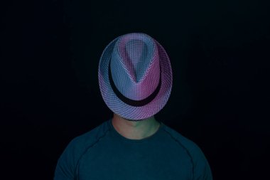 Genç adam yüzünü neon ışığıyla kaplamış siyah bir şapkayla. Minimalizm retro tarzı konsept.