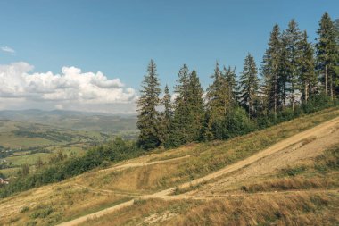 Carpatian yaz manzarası. Dağlardaki toprak yol. Mavi arkaplanda güzel dağlar.
