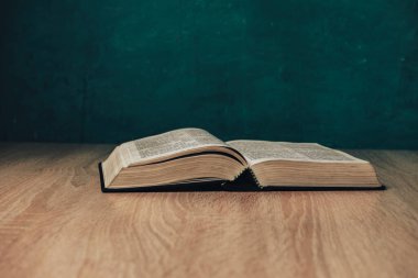 Tahta bir masada kutsal kitabı aç. Güzel yeşil duvar arkaplanı.